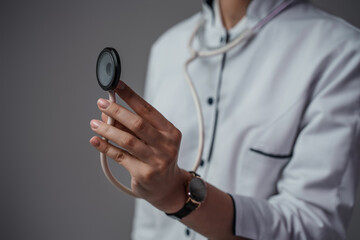 Studio shot of female doctor specialist dressed in labcoat with stethescope isolated on gray.