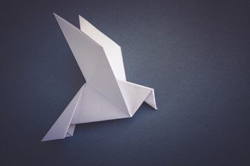 White paper dove origami isolated on a grey background