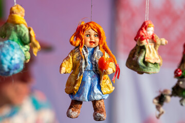 A traditional Russian puppet toy hangs on the market stall for sale.