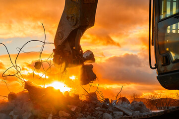 Powerful crusher destroys armored cement leftovers at sunset