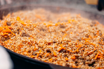 Background Yellow pilaf in cauldron with beef from street food market at festival