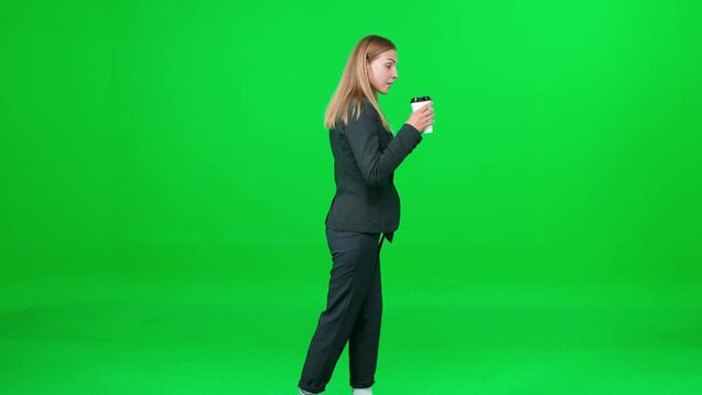 Businesswoman in a suit walking down the street and drinks coffee on a green background, a passerby on a walk, side view, chroma key template.