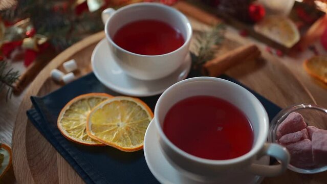 two cups of black or berry red hot english christmas tea with decor and candle