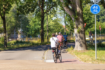 Obraz premium A group of cyclists rides along the road along the forest. Healthy lifestyle concept