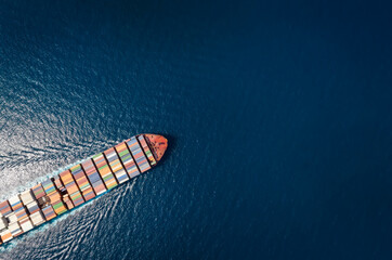 High aerial top down view of a large container cargo ship in motion over open ocean with copy space...