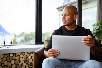 Smiling african american freelancer holding smartphone on armchair at home 