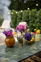 Variety of blooming flowers in vases on table at backyard