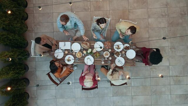 Family and friends celebrating at dinner on a rooftop terrace. Multiethnic group of people dining on the balcony on a special evening to celebrate friendship and family love and relationships