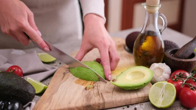 Healthy food nutrition cuisine recipes - Cutting slicing fresh avocado fruit with knife on a wooden board in a kitchen