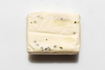 a pack of spoiled butter with mold on a white background. 
