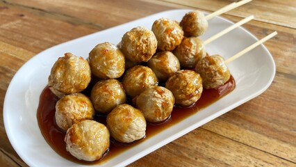 Roasted meat balls sticks in white plate.