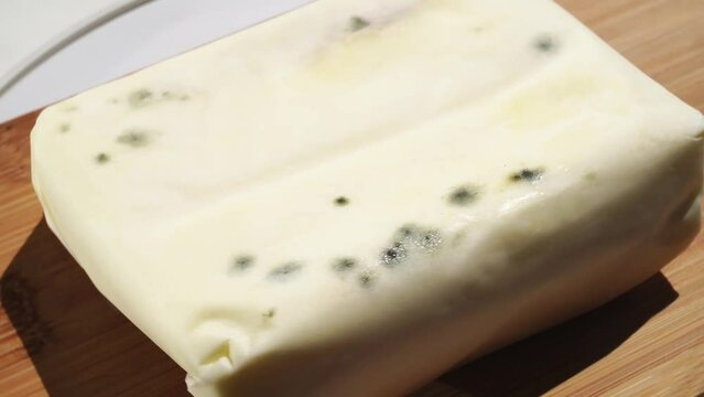 part of a pack of rotating spoiled butter with mold on a wooden board