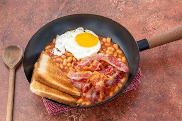 oeufs au plat, haricots à la tomate  et bacon dans une poêle