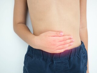 Kid boy with stomach ache on white background. Health concept. Closeup photo, blurred.