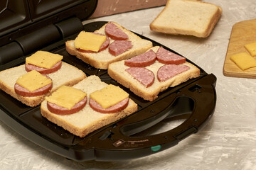 sandwich maker cheese sausage and bread on the table