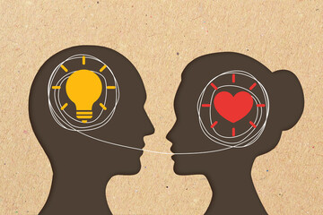 Man head silhouette with light bulb icon and woman head silhouette with heart icon - Concept of differences in communication between men and women - 527530641
