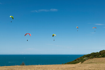 The Atlantic coastline with several paraglider pilots sustaining themselves while paragliding.