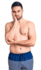 Young handsome man wearing swimwear thinking looking tired and bored with depression problems with crossed arms.