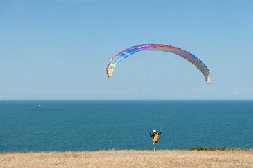 A pilot races to generate lift on takeoff as they paraglide in tandem near the Atlantic coast