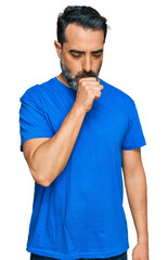 Middle aged man with beard wearing casual blue t shirt feeling unwell and coughing as symptom for cold or bronchitis. health care concept.