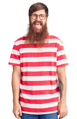 Obraz premium Handsome young red head man with long beard wearing casual clothes sticking tongue out happy with funny expression. emotion concept.
