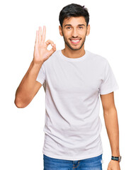 Fototapeta premium Young handsome man wearing casual white tshirt smiling positive doing ok sign with hand and fingers. successful expression.