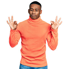 Fototapeta premium Young black man wearing orange turtleneck sweater relax and smiling with eyes closed doing meditation gesture with fingers. yoga concept.