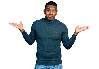 Young black man wearing casual sweater clueless and confused with open arms, no idea and doubtful...