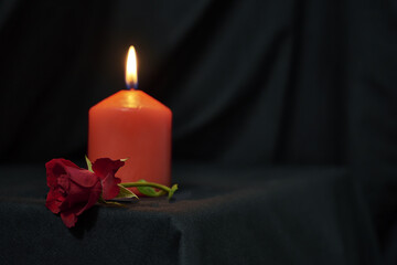 a red burning candle and a red rose on a black background copy space gothic style