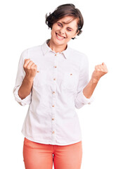 Beautiful young woman with short hair wearing elegant white shirt excited for success with arms raised and eyes closed celebrating victory smiling. winner concept.