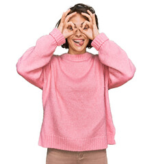 Young hispanic woman wearing casual clothes doing ok gesture like binoculars sticking tongue out, eyes looking through fingers. crazy expression.