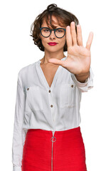 Young hispanic woman wearing business style and glasses doing stop sing with palm of the hand. warning expression with negative and serious gesture on the face.