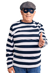 Senior handsome man wearing burglar mask and t-shirt smiling cheerful offering palm hand giving assistance and acceptance.