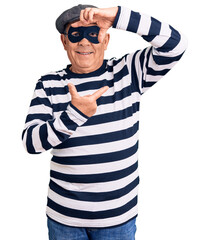 Senior handsome man wearing burglar mask and t-shirt smiling making frame with hands and fingers...