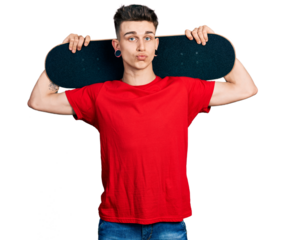 Young caucasian boy with ears dilation holding skate over shoulders looking at the camera blowing a kiss being lovely and sexy. love expression.