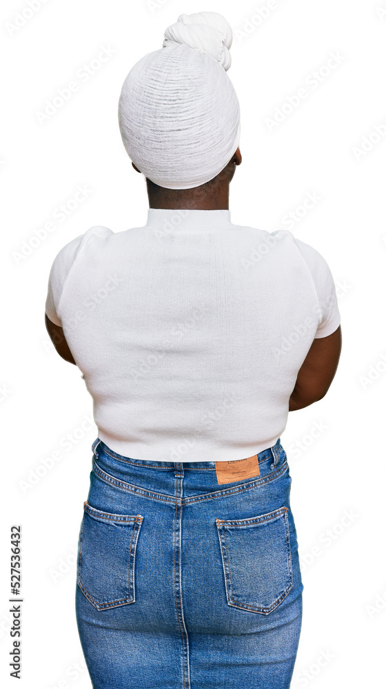 Sticker Young african woman with turban wearing hair turban over isolated background standing backwards looking away with crossed arms