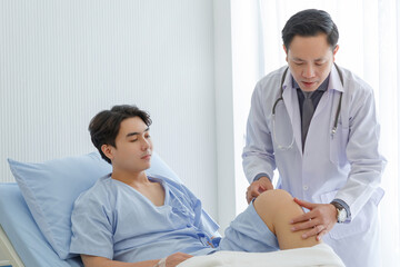 Obraz premium Senior doctor and young male patient who lie on the bed while checking symptom, consult and explain in hospital wards.