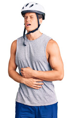 Young handsome man wearing bike helmet with hand on stomach because nausea, painful disease feeling unwell. ache concept.