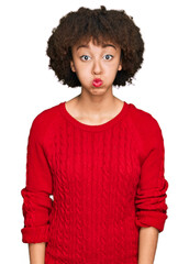 Young hispanic girl wearing casual clothes puffing cheeks with funny face. mouth inflated with air, crazy expression.