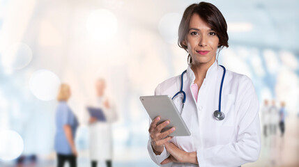 Attractive female doctor sing toucpad while standing at the hospital