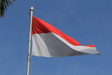 The Indonesian flag is flying, red and white on a blue sky background