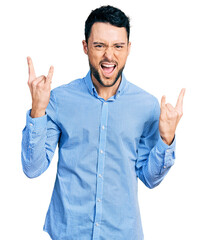 Hispanic man with beard wearing casual business shirt shouting with crazy expression doing rock symbol with hands up. music star. heavy concept.