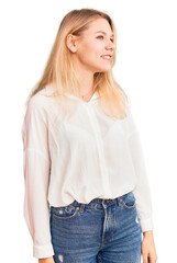 Obraz premium Young beautiful blonde woman wearing casual shirt looking away to side with smile on face, natural expression. laughing confident.