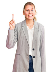 Young beautiful blonde woman wearing elegant jacket showing and pointing up with finger number one while smiling confident and happy.