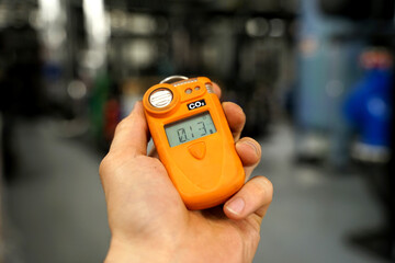 Co2 safety personal portable gas monitor and detector in heavy indrustry worker's hand