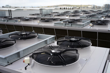Large row of industrial condensers with fans on roof used in air conditioning, refrigeration, heat...