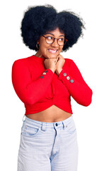Young african american girl wearing casual clothes and glasses laughing nervous and excited with hands on chin looking to the side