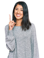 Beautiful asian young woman wearing casual clothes showing and pointing up with finger number one while smiling confident and happy.