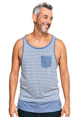 Middle age grey-haired man wearing casual style with sleeveless shirt looking away to side with smile on face, natural expression. laughing confident.