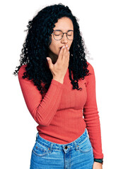 Young hispanic woman with curly hair wearing glasses bored yawning tired covering mouth with hand. restless and sleepiness.